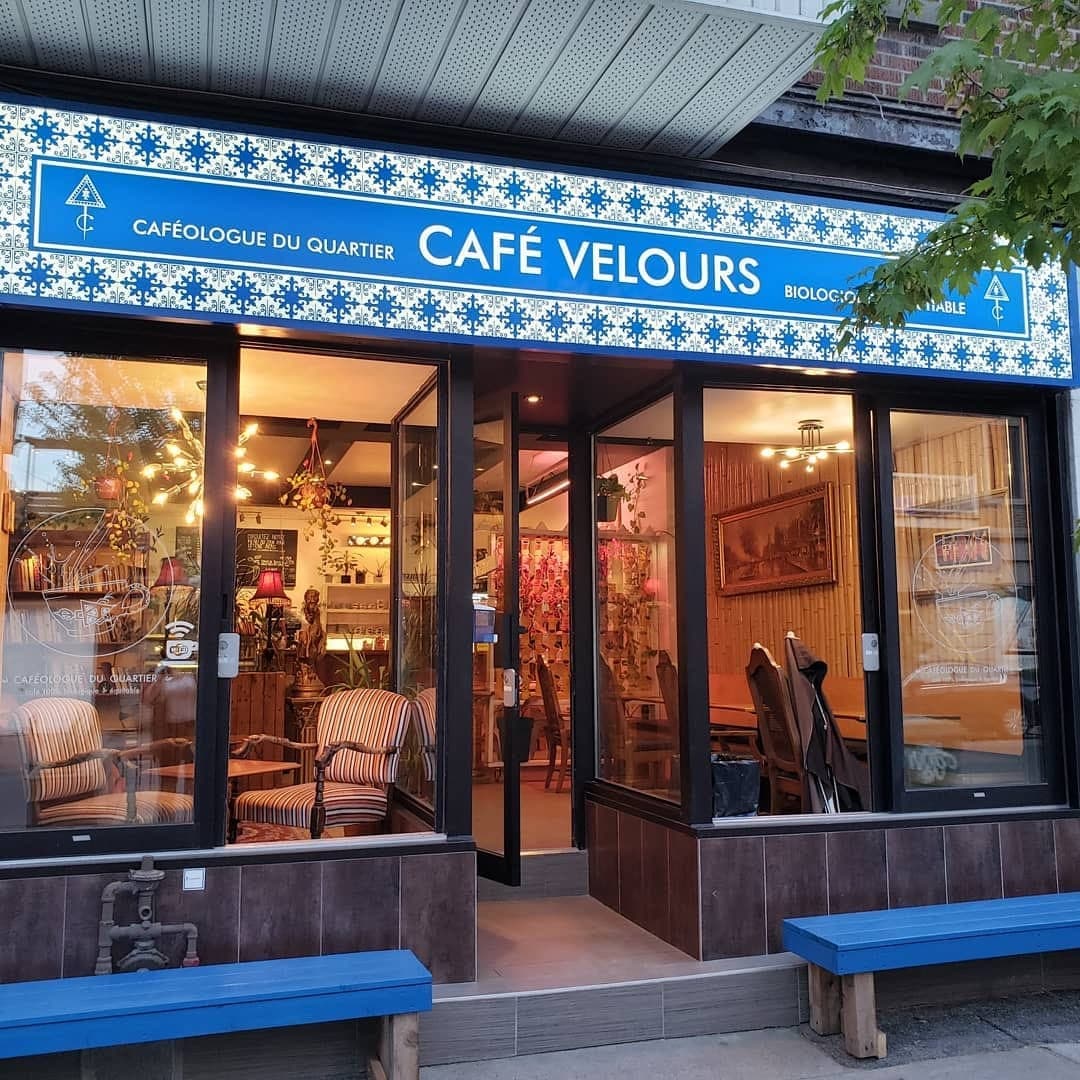 La façade du Café Velours en soirée, enseigne bleue illuminée